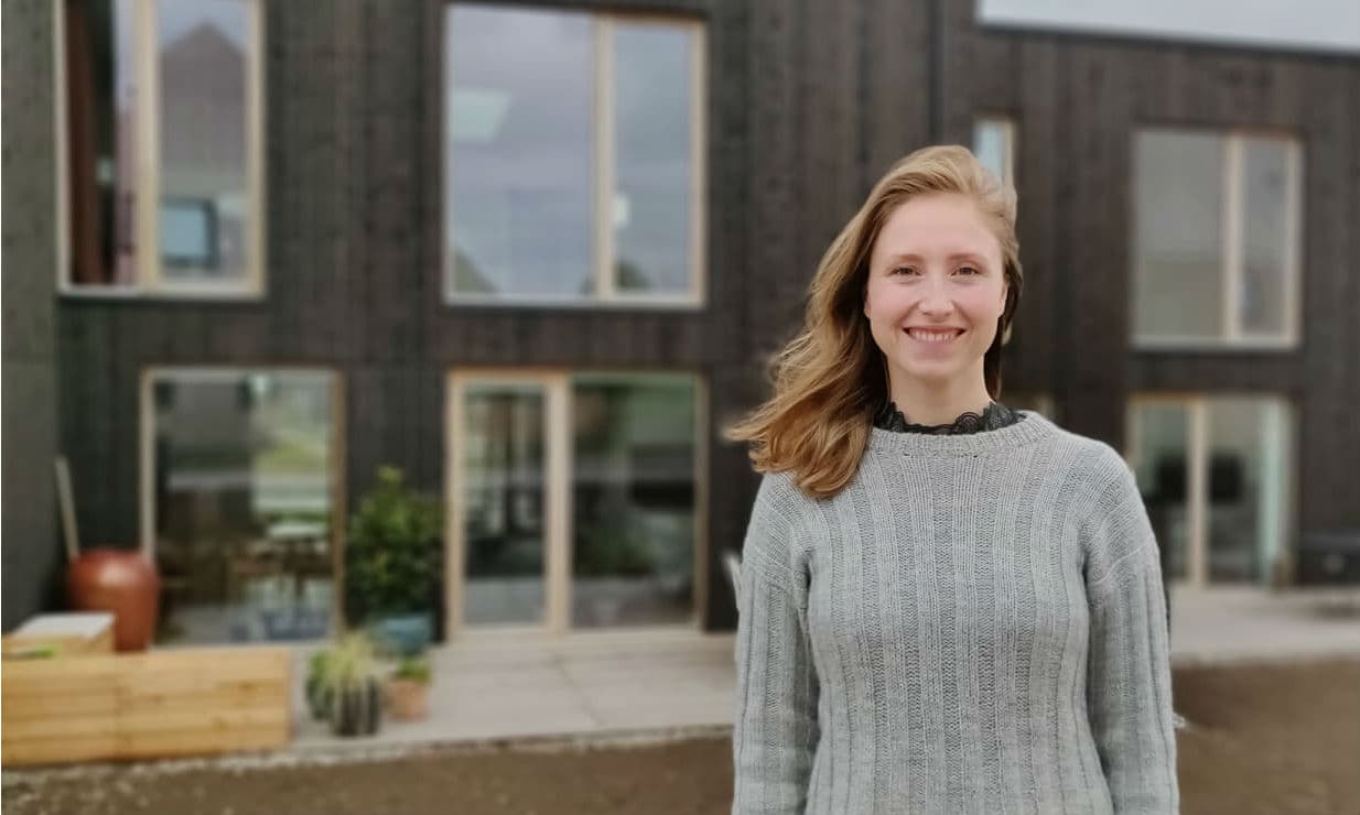 Mette Møller Herskind foran sit sorte rækkehus tegnet af Aart Architects. Hun ser byens bæredygtige aspekt som et plus, men det er fællesskabet med naboerne, der virkelig får Nye til at skille sig ud.